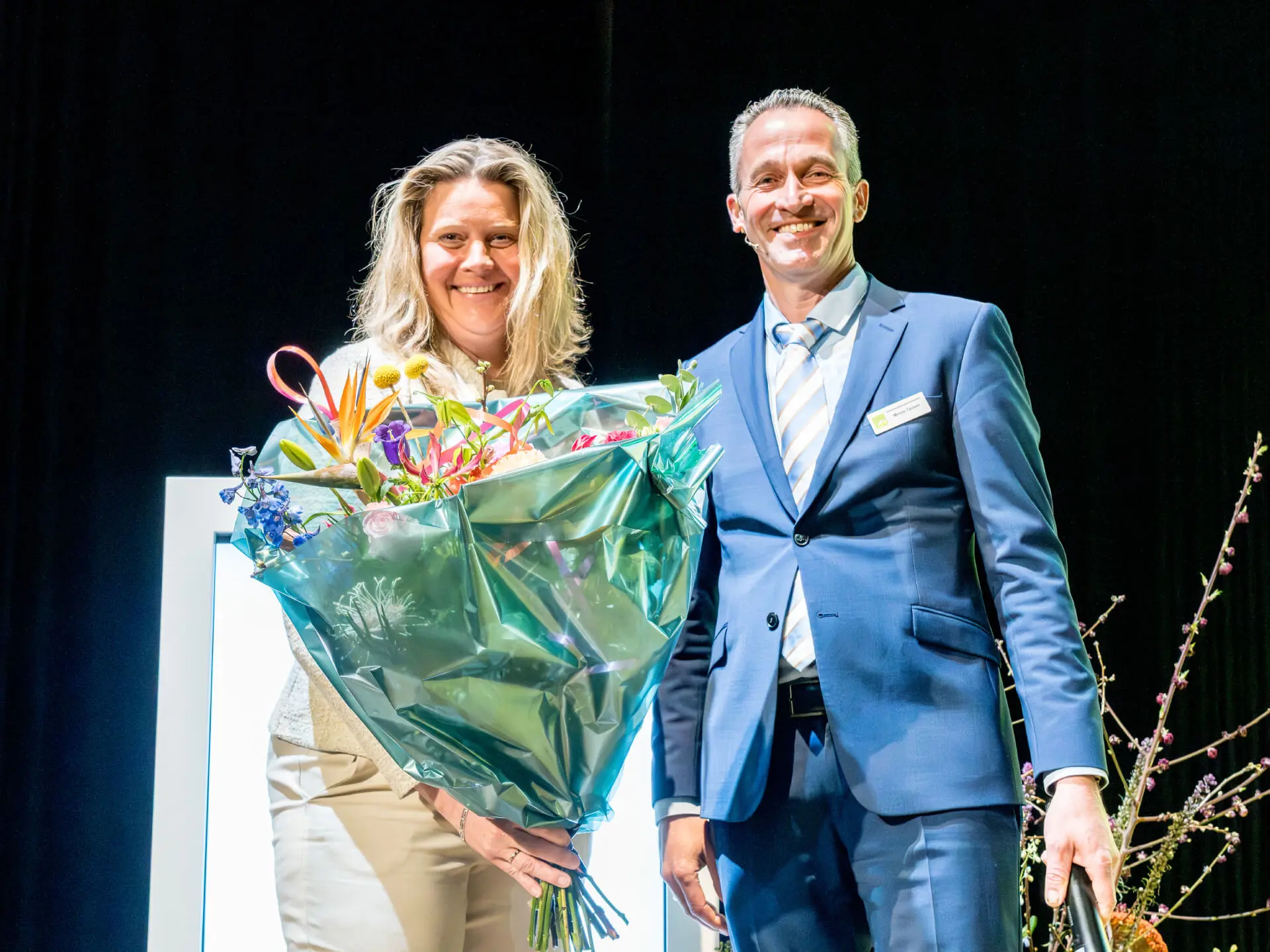 Menso Tijssen overhandigt bos bloemen aan aftredend bestuurslid Melanda Bouw